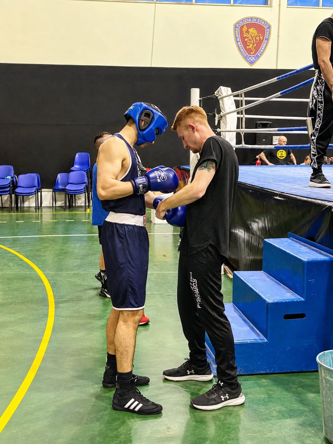 Il maestro allaccia i guantoni a un atleta prima del match